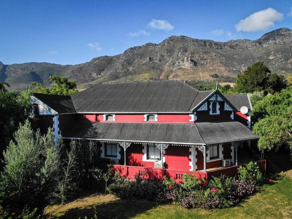 a red and black house with mountains in the background at Ruby Rose in Riebeek-Wes