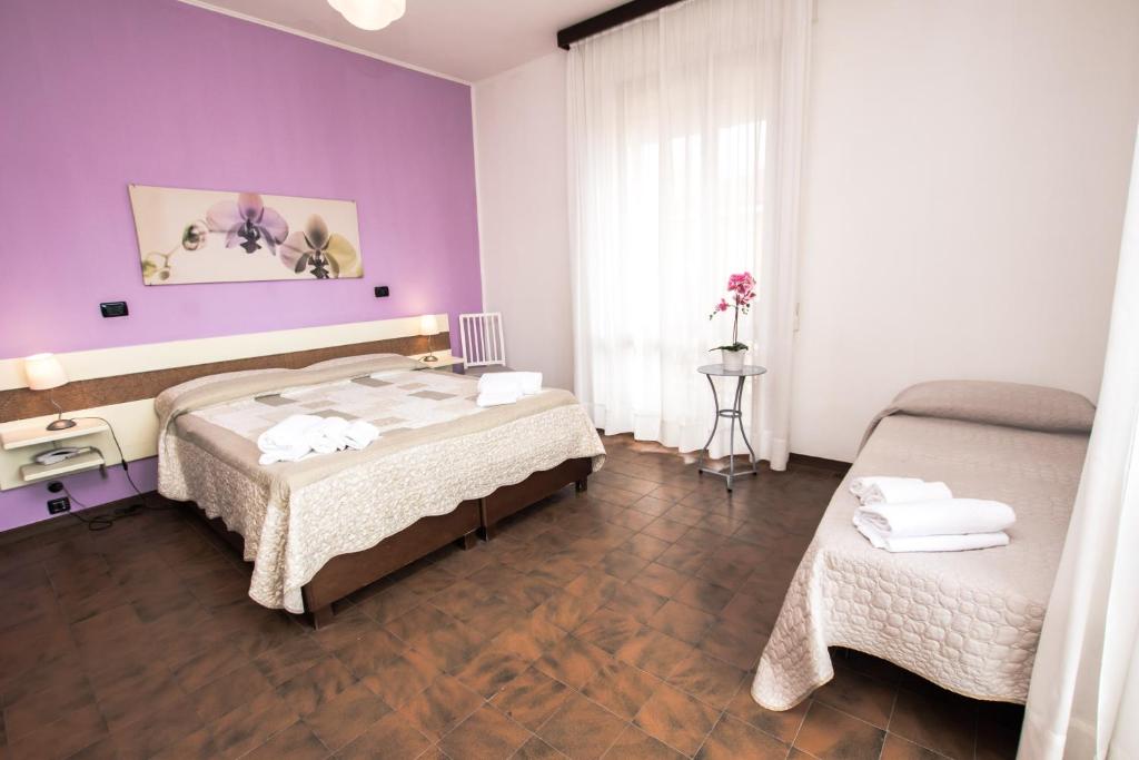 1 Schlafzimmer mit 2 Betten und einer lila Wand in der Unterkunft Hotel Giulia in Marina di Massa