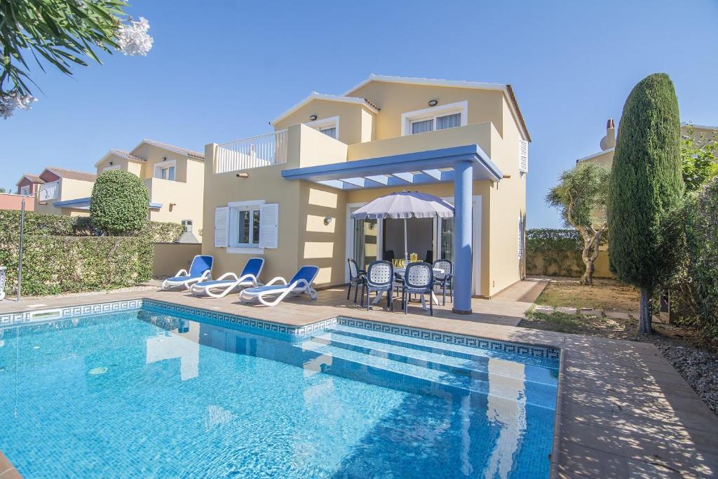 a villa with a swimming pool in front of a house at Villas Amarillas in Cala Blanca