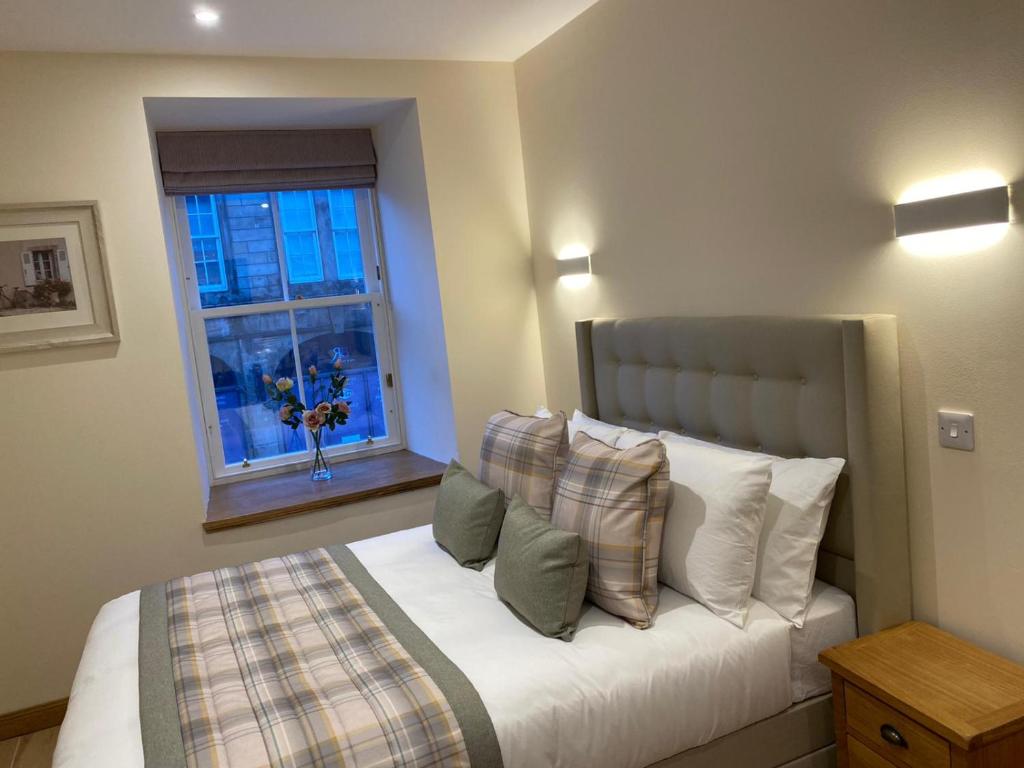 1 dormitorio con cama con almohadas y ventana en Waverley Inn Holiday Apartments en Inverness