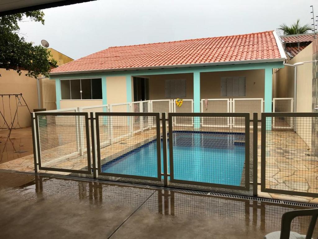 a fence around a swimming pool in front of a house at Espaço Laranjeira in Campo Grande