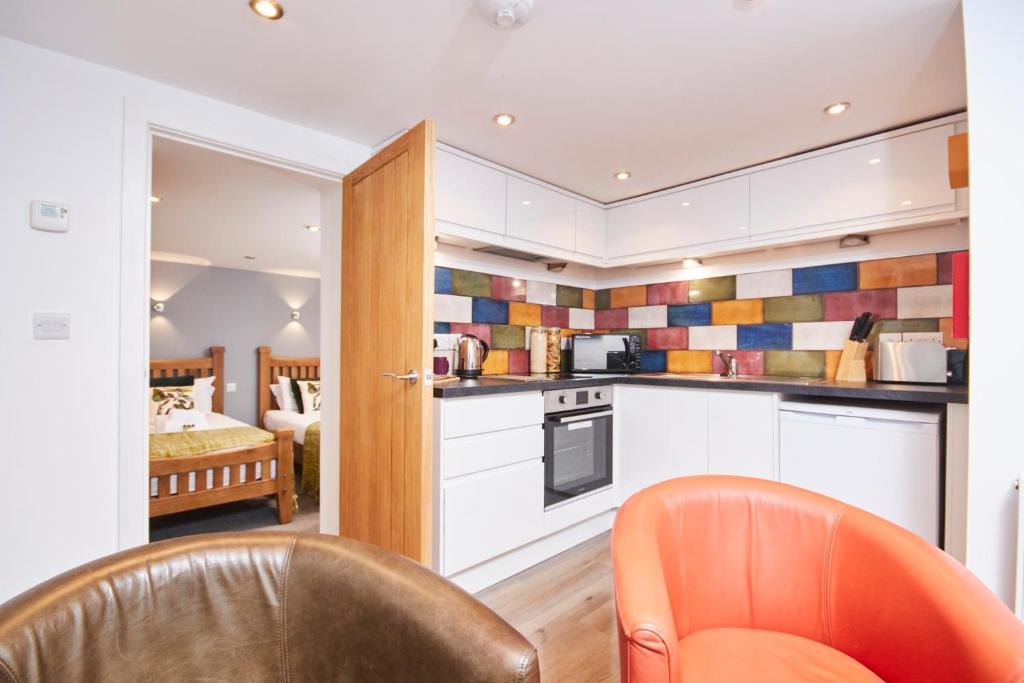 a kitchen with white cabinets and an orange chair at Number 57 in Kegworth