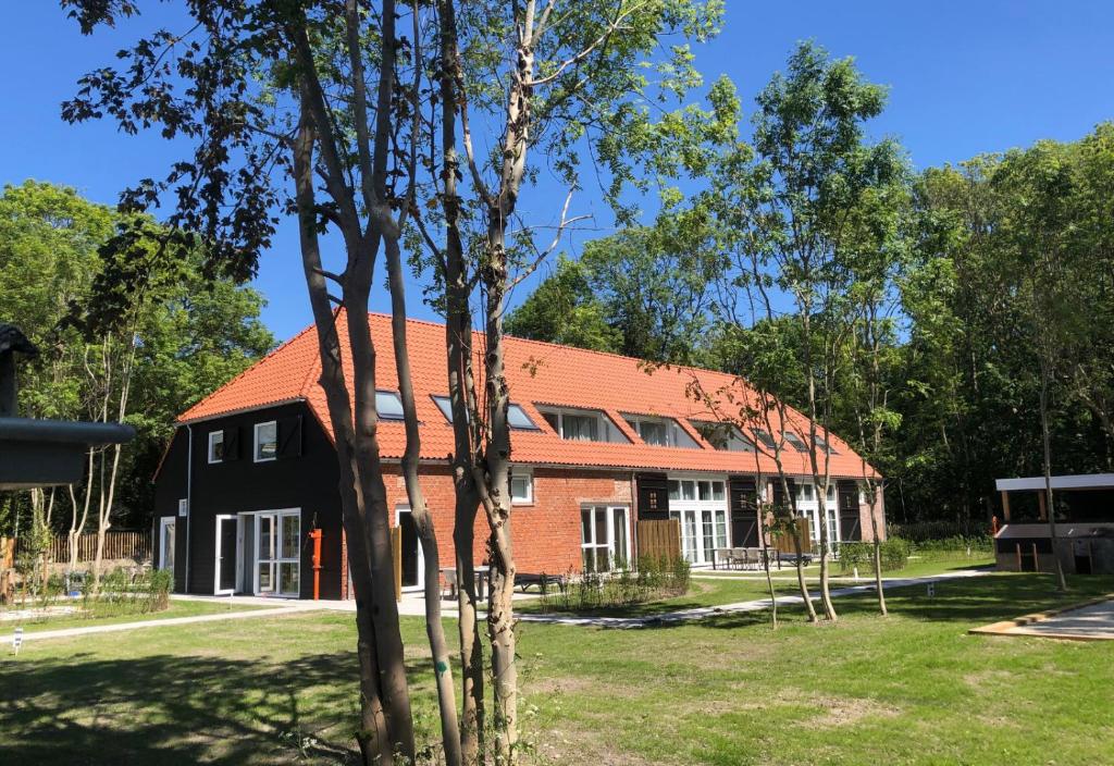 une grande maison avec un toit rouge et des arbres dans l'établissement Hofstede Moesbosch I Kloeg Collection, à Koudekerke