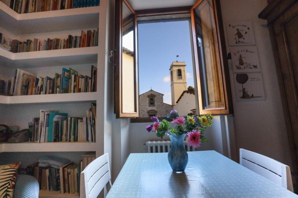 un jarrón de flores sentado en una mesa con una ventana en B&B "La Pieve" - Locanda per Viandanti, en San Piero a Sieve