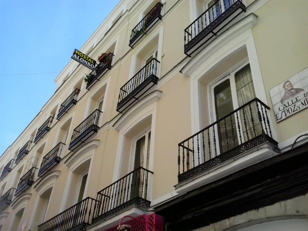 un edificio alto de color blanco con balcones y ventanas en Hostal Alonso, en Madrid