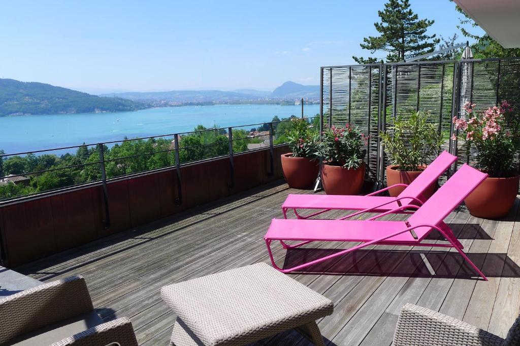 balcón con sillas rosas y vistas al agua en Le Clos Du Lac - location de chambres, en Veyrier-du-Lac
