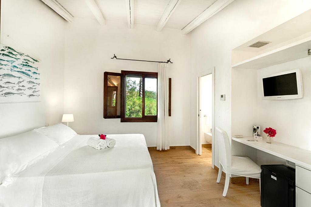 a white bedroom with a bed and a desk at Hotel Villa Mediterranea in Noto Marina