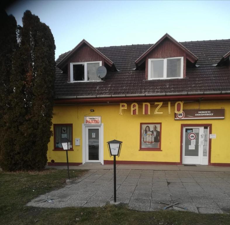 een geel gebouw met een parkeermeter ervoor bij Fekete Macska Panzió in Tata