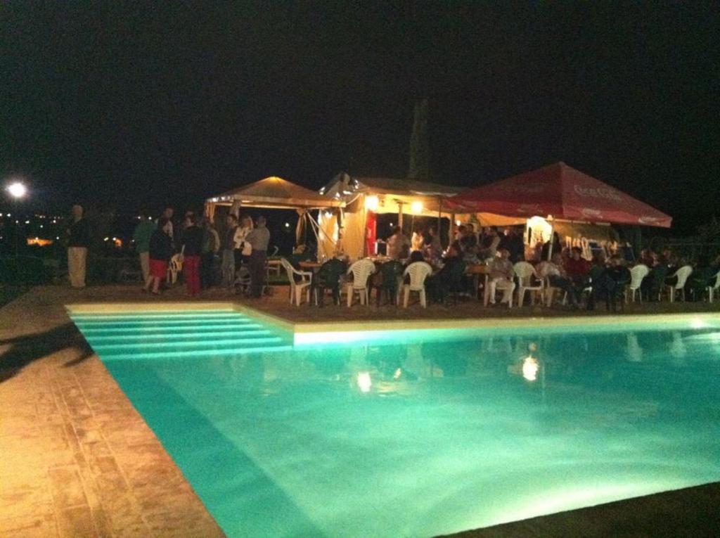 a group of people standing around a pool at night at Agriturismo Zaffamaro in Beroide