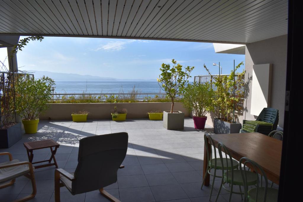 un patio avec des chaises et une table et une vue sur l'océan dans l'établissement AJACCIO SPLENDIDE VUE MER, à Ajaccio