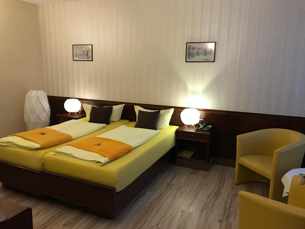 ein Schlafzimmer mit einem Bett, zwei Lampen und einem Stuhl in der Unterkunft Hotel Schöne Aussicht in Weißenfels
