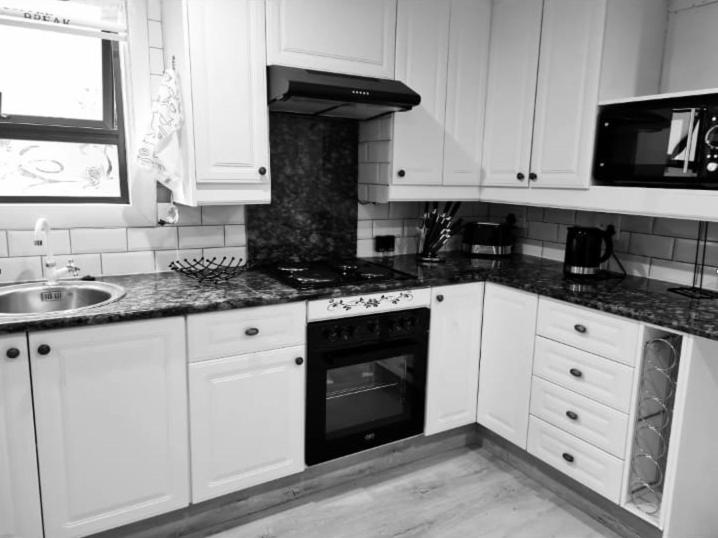 a kitchen with white cabinets and a sink and an oven at Cozy Cabin in Midrand