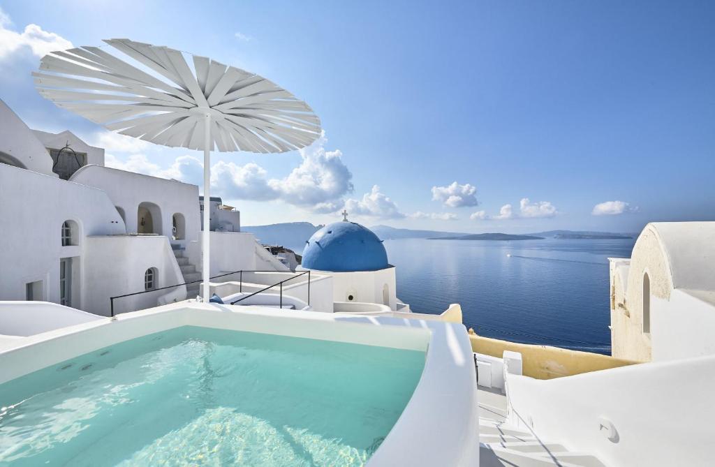 a swimming pool on the side of a house with the ocean at Cave Suite Oia in Oia