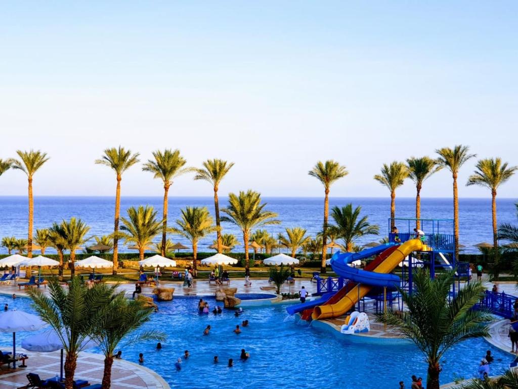 a pool at a resort with palm trees and a slide at Ecotel Dahab Bay View Resort in Dahab