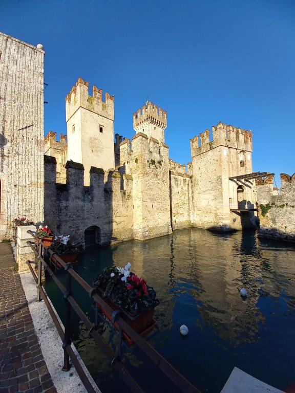 a castle with a bunch of flowers in the water at Il Nido del Cigno in Sirmione