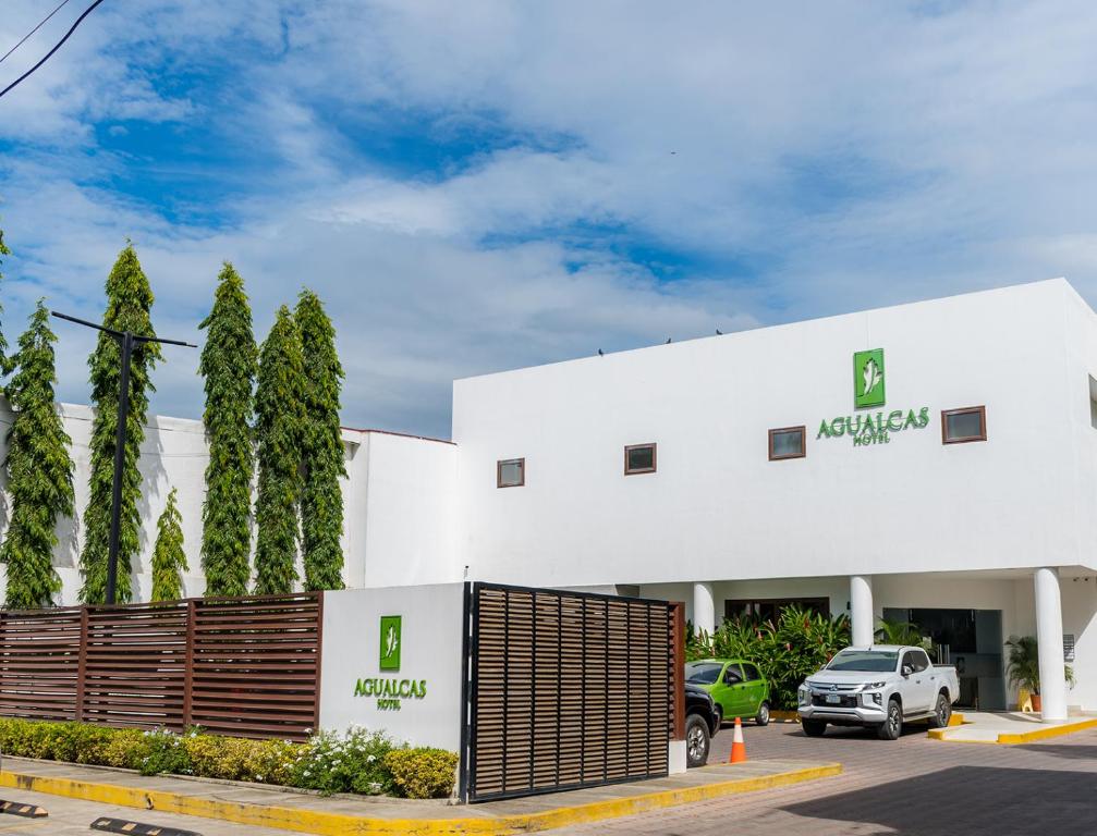 Biały budynek z samochodem zaparkowanym przed nim w obiekcie Hotel Agualcas w mieście Managua