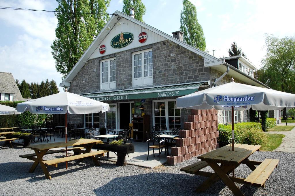 un restaurant avec des tables et des parasols en face de celui-ci dans l'établissement Auberge Grill Le Freyr, à Dinant