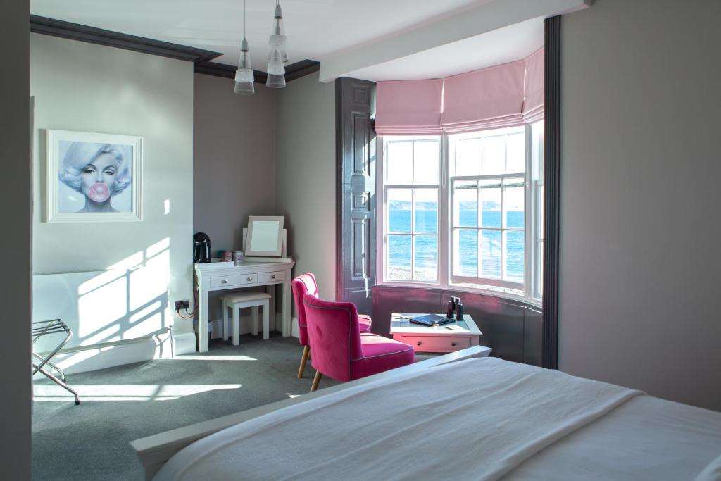 Schlafzimmer mit einem Bett, einem Schreibtisch und einem rosa Stuhl in der Unterkunft The View on the terrace in Weymouth