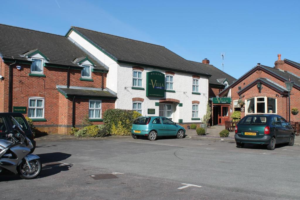 two cars parked in a parking lot in front of a building at The Villa Express in Kirkham