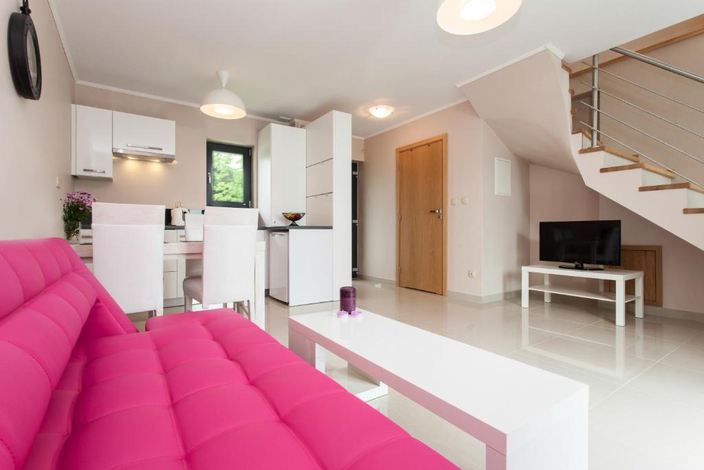 a living room with a pink couch and a kitchen at Nautilus Apartamenty in Rewal