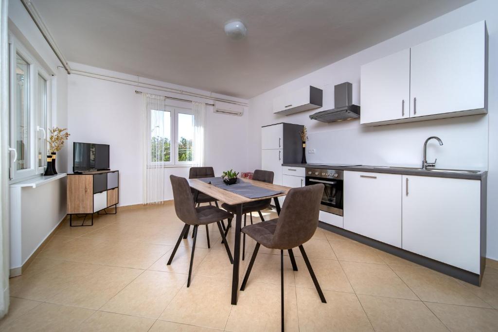 a kitchen and dining room with a table and chairs at Apartmani Milena in Rab