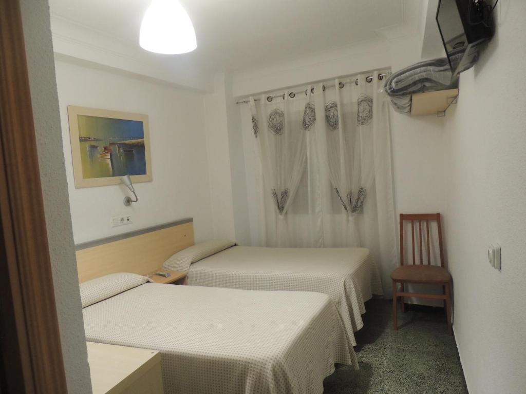a hotel room with a bed and a dresser at Hostal Cumbre in Zaragoza