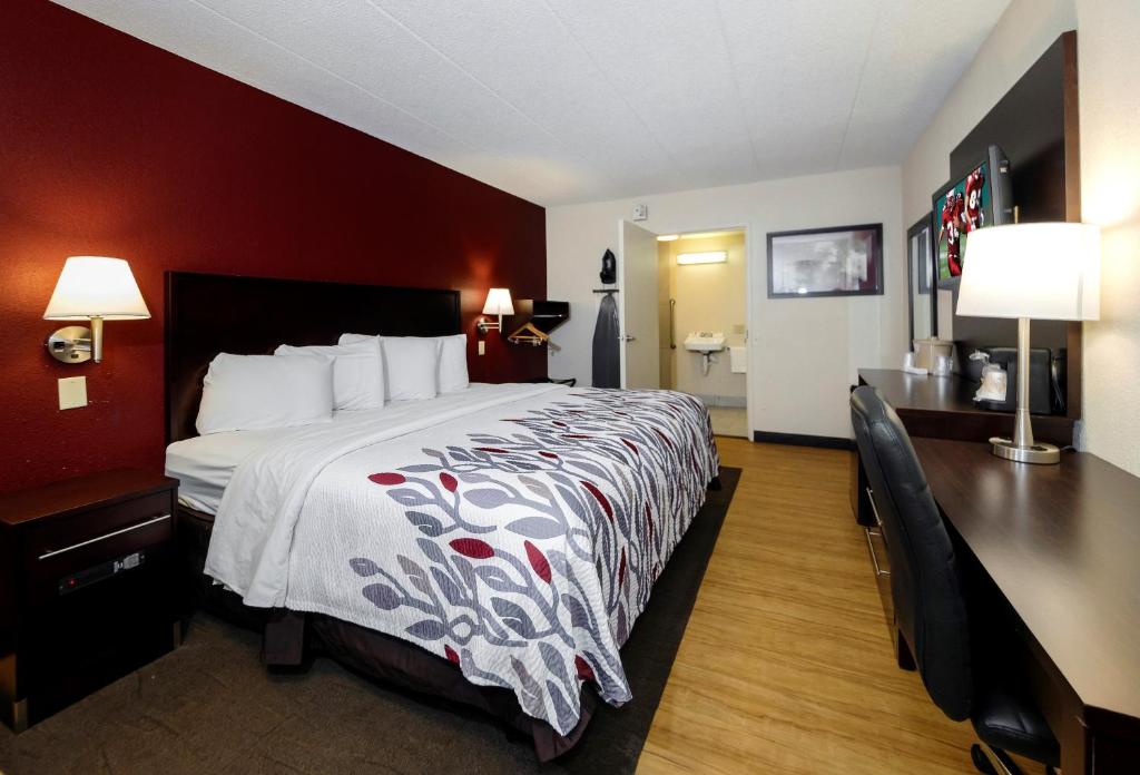 ein Hotelzimmer mit einem großen Bett und einem Schreibtisch in der Unterkunft Red Roof Inn Detroit - Troy in Troy