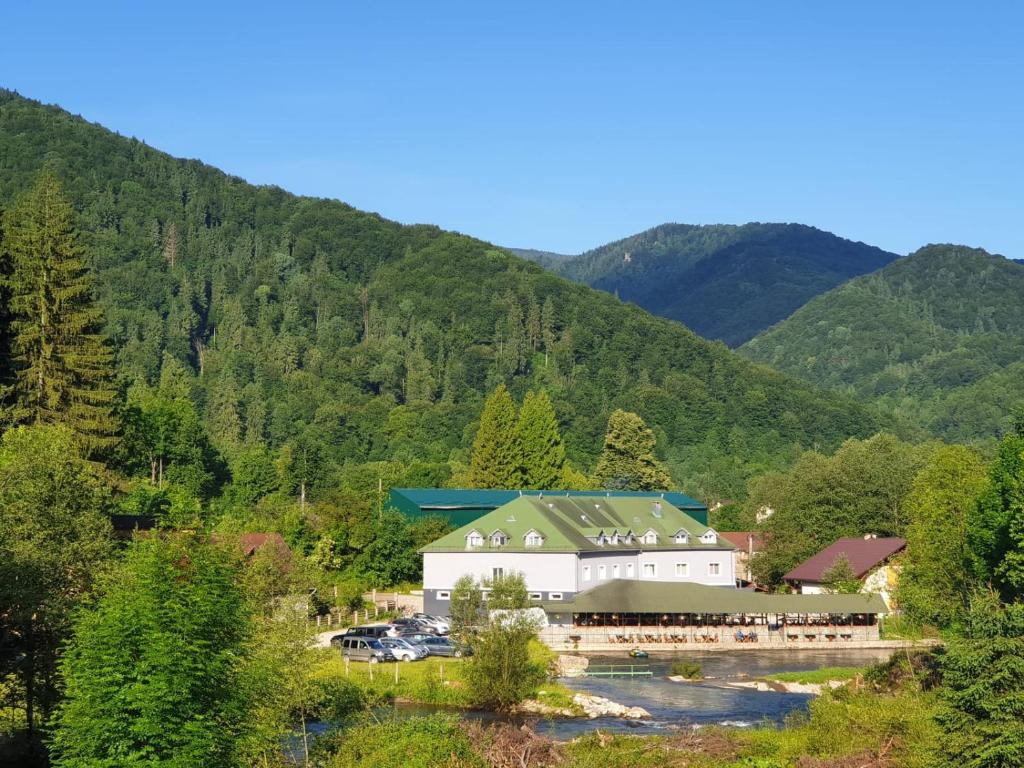 um grande edifício branco com um telhado verde nas montanhas em HOTEL HO2 POIANA MARULUI em Poiana Mărului