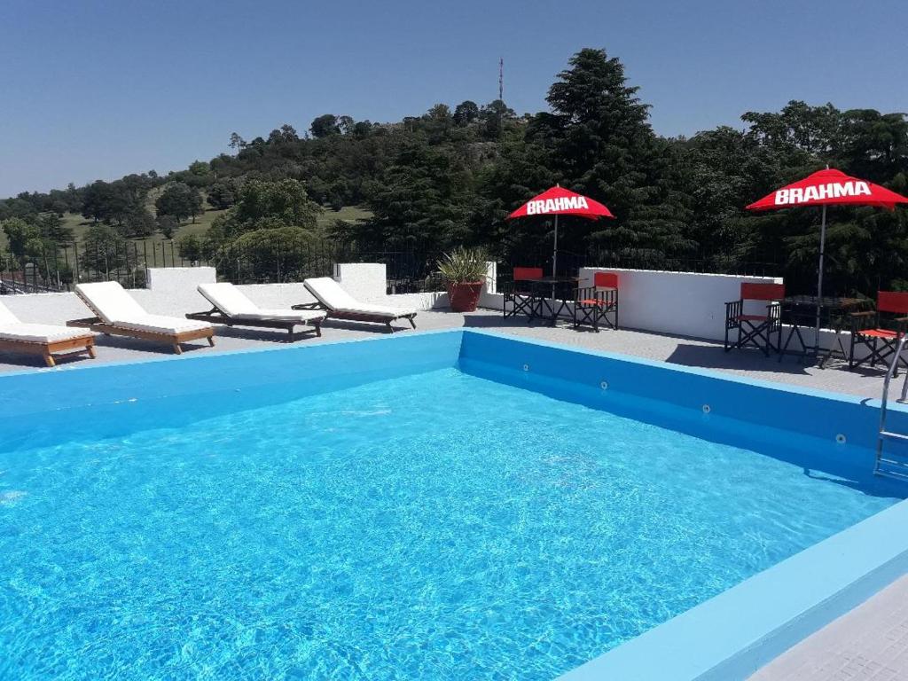 una piscina azul con sillas y sombrillas en Hotel Hermitage en Tandil