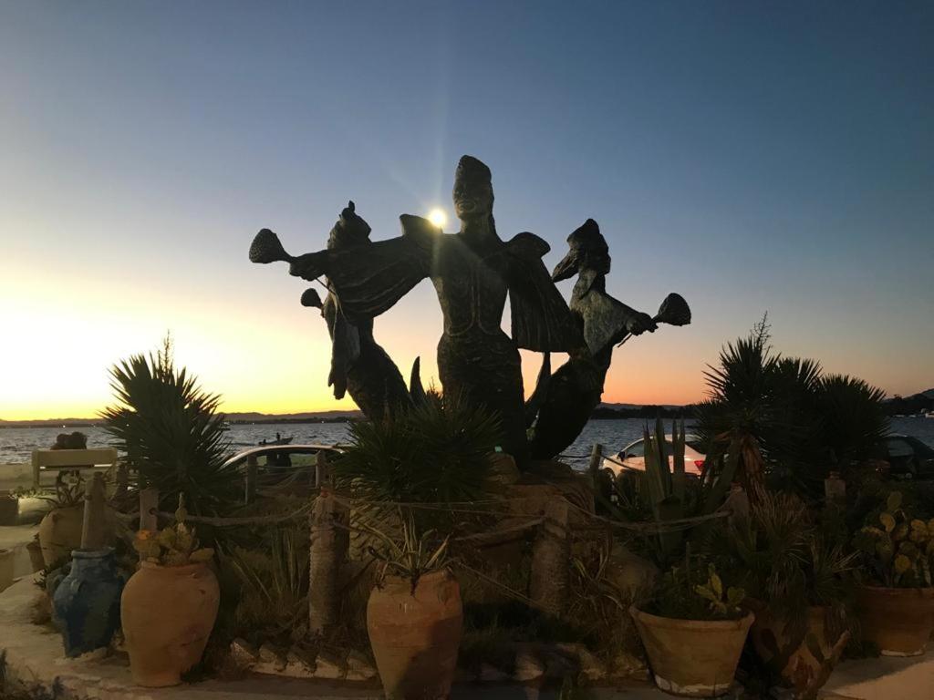 a statue of people on a beach with the sunset in the background at Villa Phoenicia in Hammamet