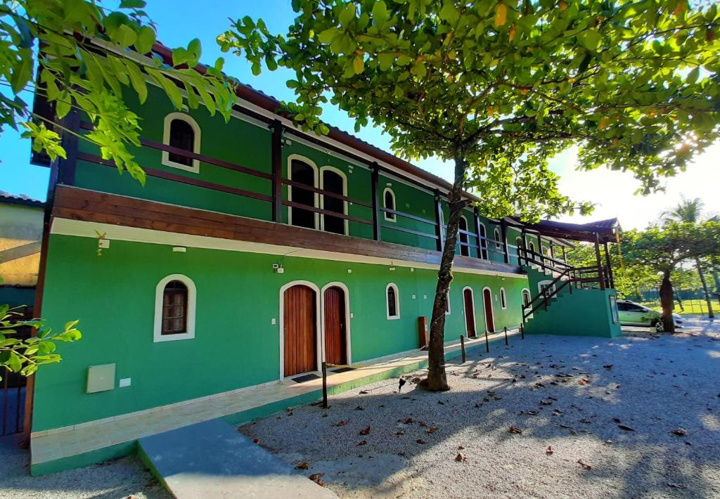 un edificio verde con un árbol delante de él en Morada dos Colibris en Boicucanga