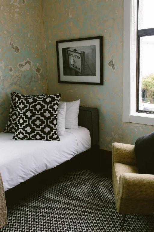 a bedroom with a bed with a pillow and a chair at The Convent Hotel in Auckland