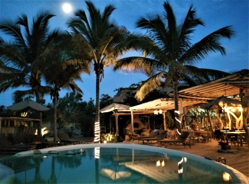 a pool at night with palm trees and a moon at La Posada De Los Tumpis in Bocapán