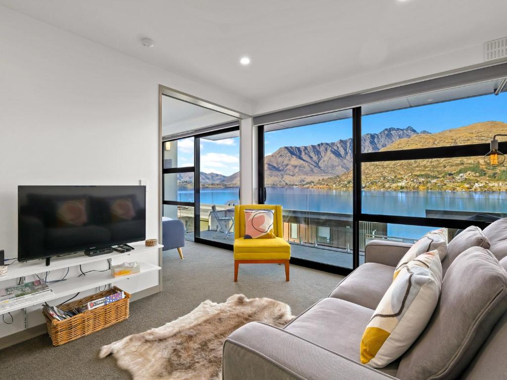 a living room with a couch and a tv and mountains at Residence du Lac by Staysouth in Queenstown
