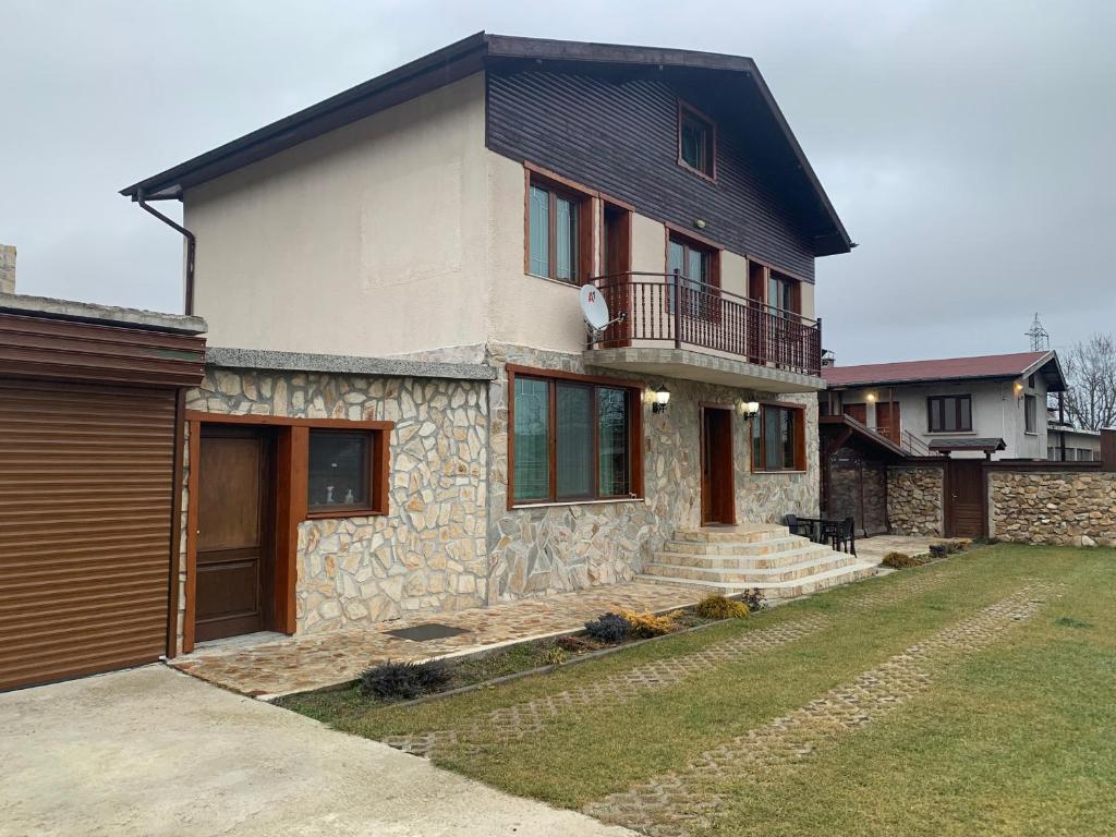 uma casa de pedra com uma varanda e um quintal em Guest house Haciendata em Samokov