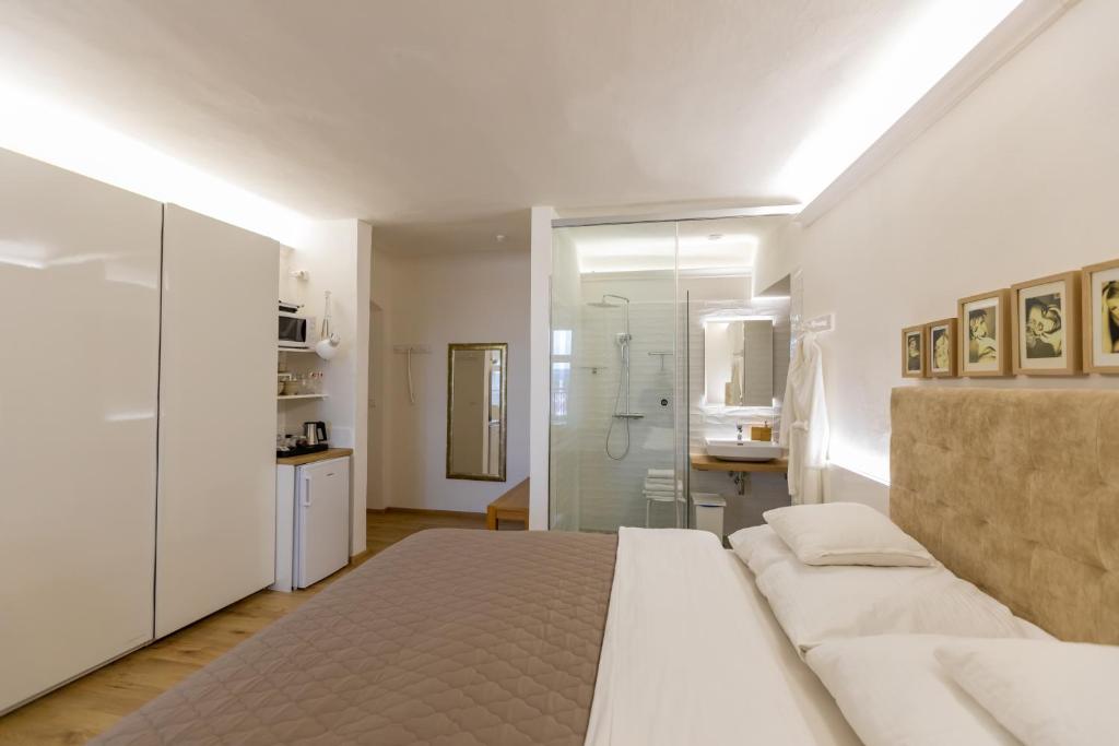 a white bedroom with a bed and a shower at Palác Daun - Studio Apartments in Znojmo