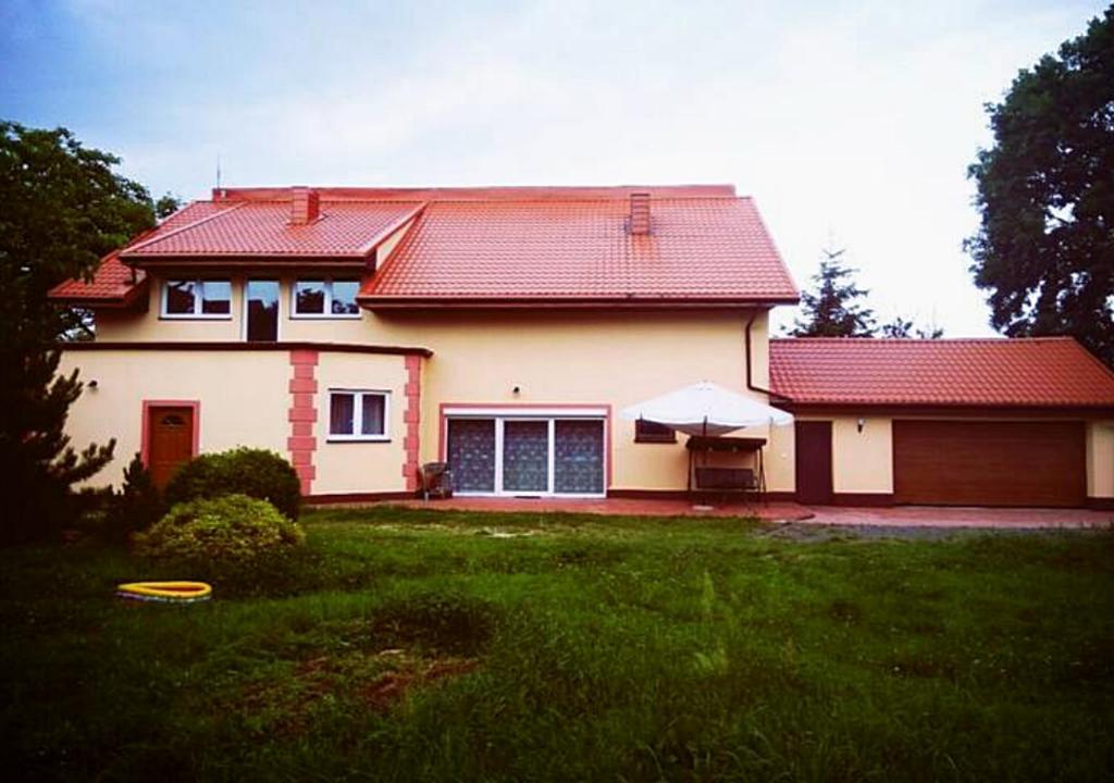 una casa con techo rojo y patio verde en Apartament Gorki Male, en Tuszyn