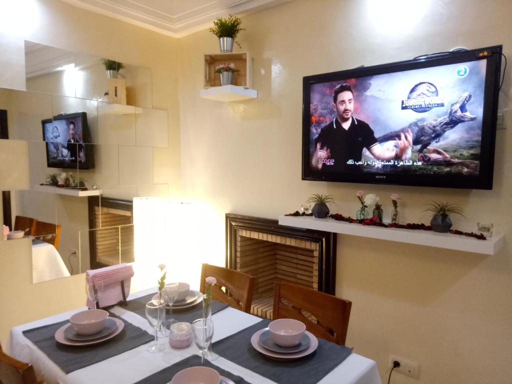 une salle à manger avec une table et une télévision murale dans l'établissement Apartment with Terrace, à Casablanca