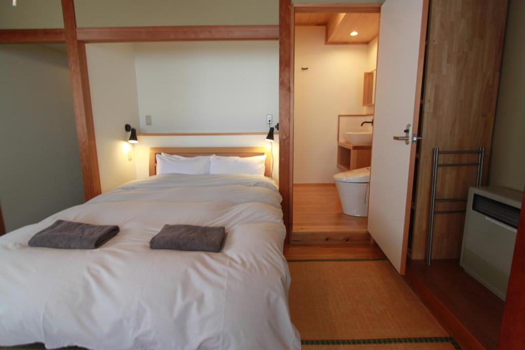 a bedroom with a large white bed with two pillows on it at Alpine Villa Nozawa in Nozawa Onsen