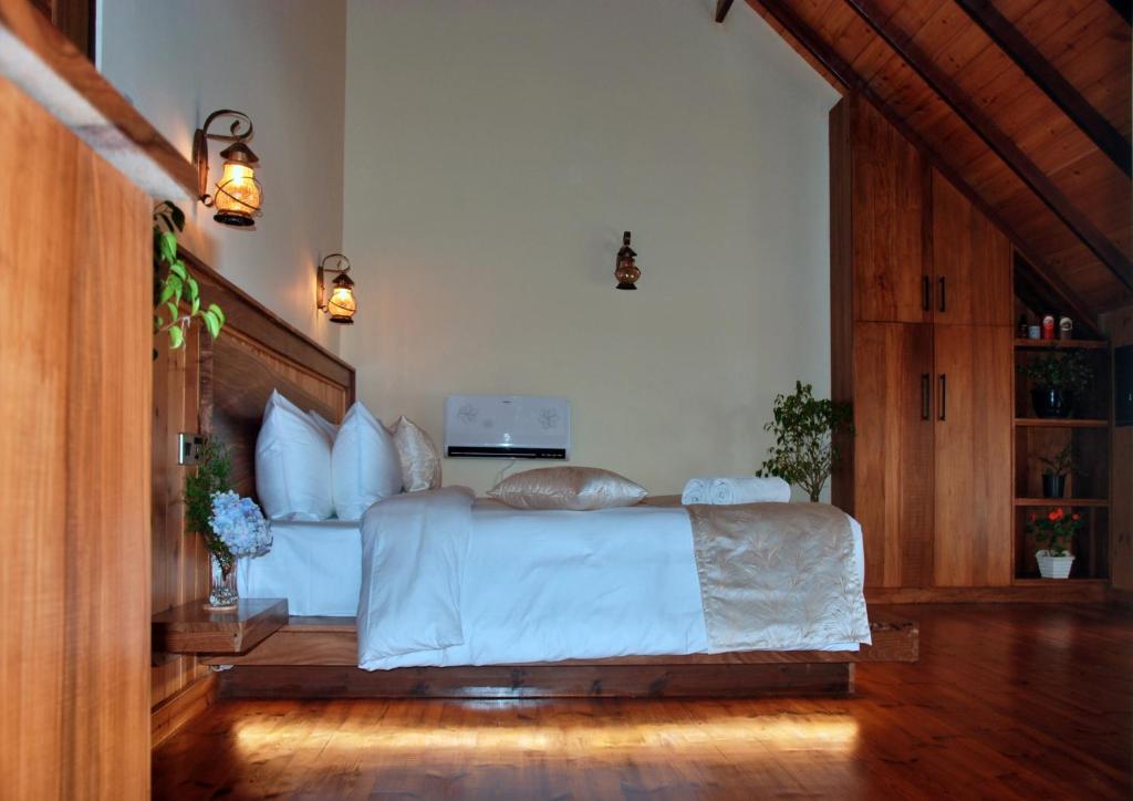 a bedroom with a large bed with white sheets at Cottage San Francesco in Nuwara Eliya
