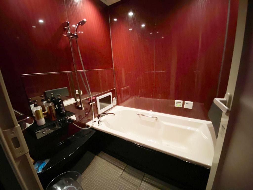 a bathroom with a large tub and red walls at Wink in Saijo