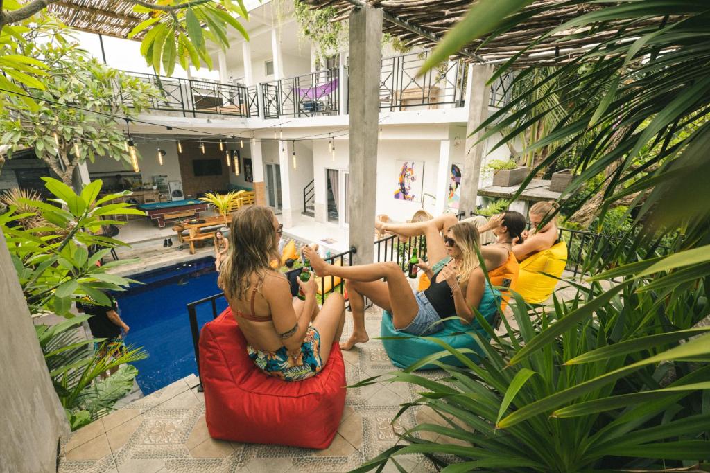 un grupo de personas sentadas alrededor de una piscina en The Hostel Canggu en Canggu