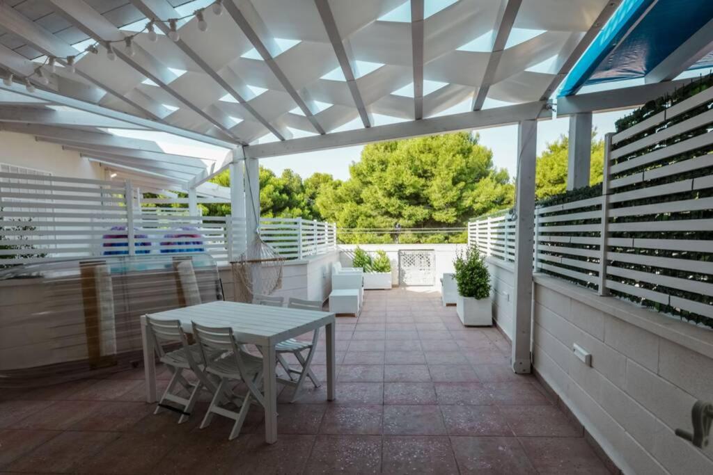eine Terrasse mit einer weißen Pergola sowie einem Tisch und Stühlen in der Unterkunft "LUMINARIA" casa nuova in Salento fronte mare!!! in Sant'Isidoro