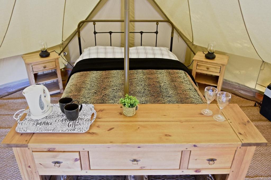a bedroom with a bed and a table with wine glasses at Glamping at Camping La Source in Saint-Pierre-dʼArgençon