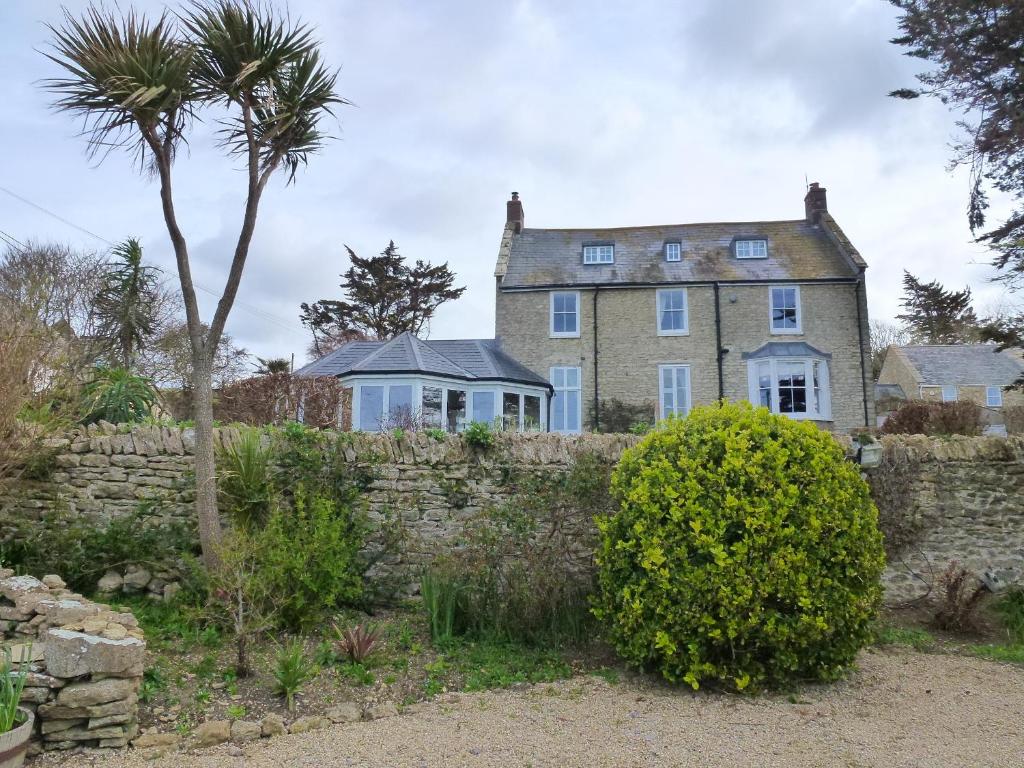 an old house with a stone wall and a palm tree at The Manor House in Puncknowle