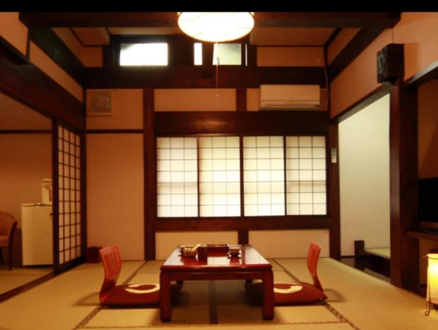 Ryokan Murayama في تاكاياما: غرفة معيشة مع طاولة وكرسيين