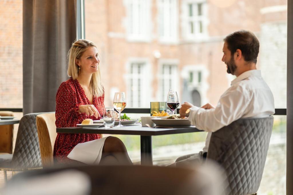 a man and woman sitting at a table with wine glasses at Van Der Valk Sélys Liège Hotel &amp; Spa in Liège