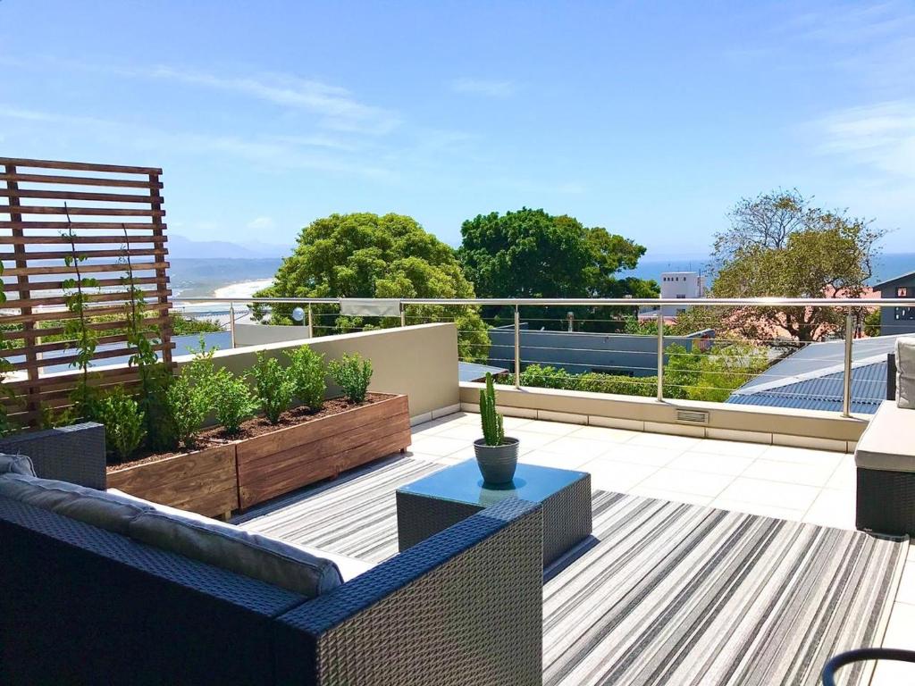 a rooftop patio with a view of the ocean at Plett Holiday Apartment in Plettenberg Bay