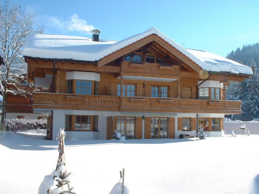 ein großes Holzhaus mit Schnee auf dem Boden in der Unterkunft Ferienwohnung Kronshage in Reit im Winkl