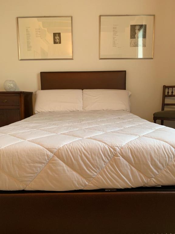 1 cama blanca en un dormitorio con 2 cuadros en la pared en Maison Ancienne - Self check-in, en Bérgamo